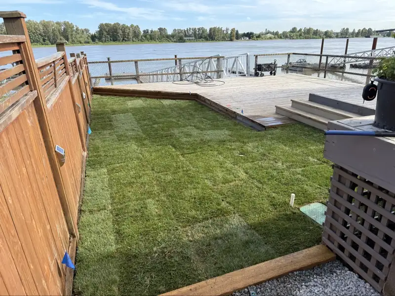 Fresh sod installed by Top Gun Landscaping beside a wooden deck overlooking the river